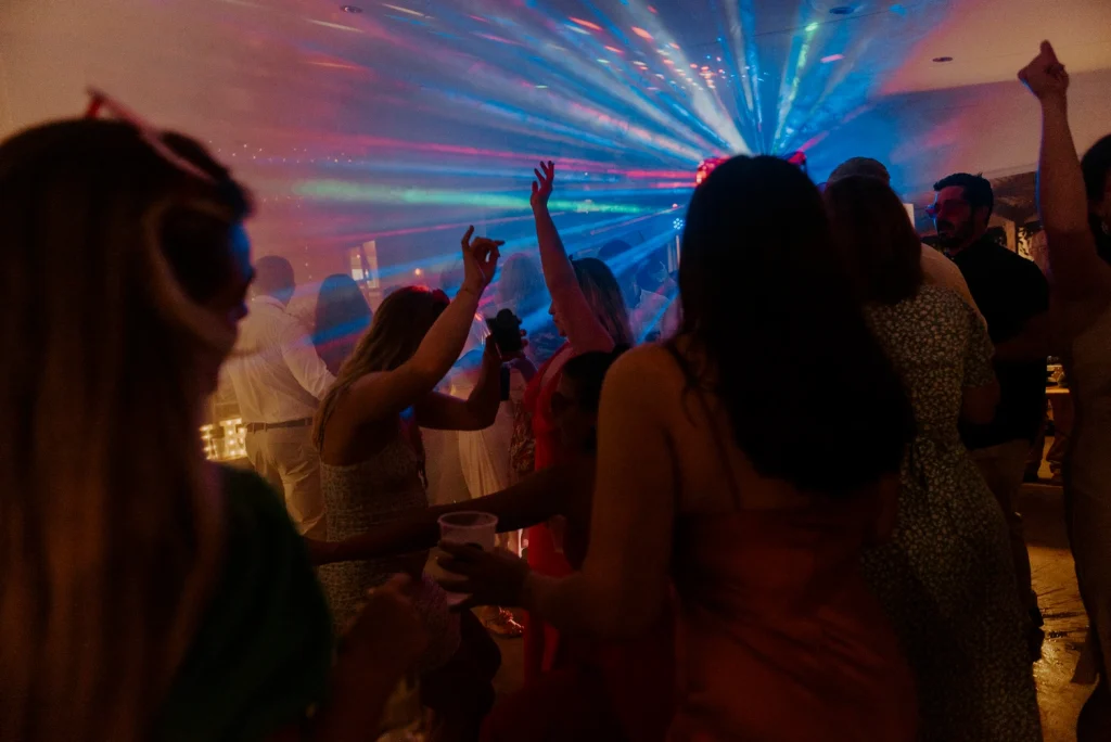 Wedding guests dancing under vibrant DJ lighting and atmospheric effects during a packed wedding dancefloor celebration on the KZN South Coast