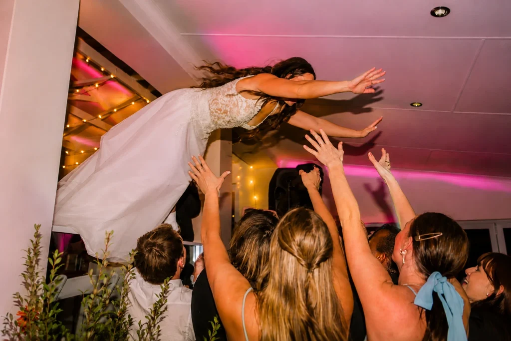 Bride crowd surfing above wedding guests during a lively wedding dancefloor celebration at Clearwater Farm