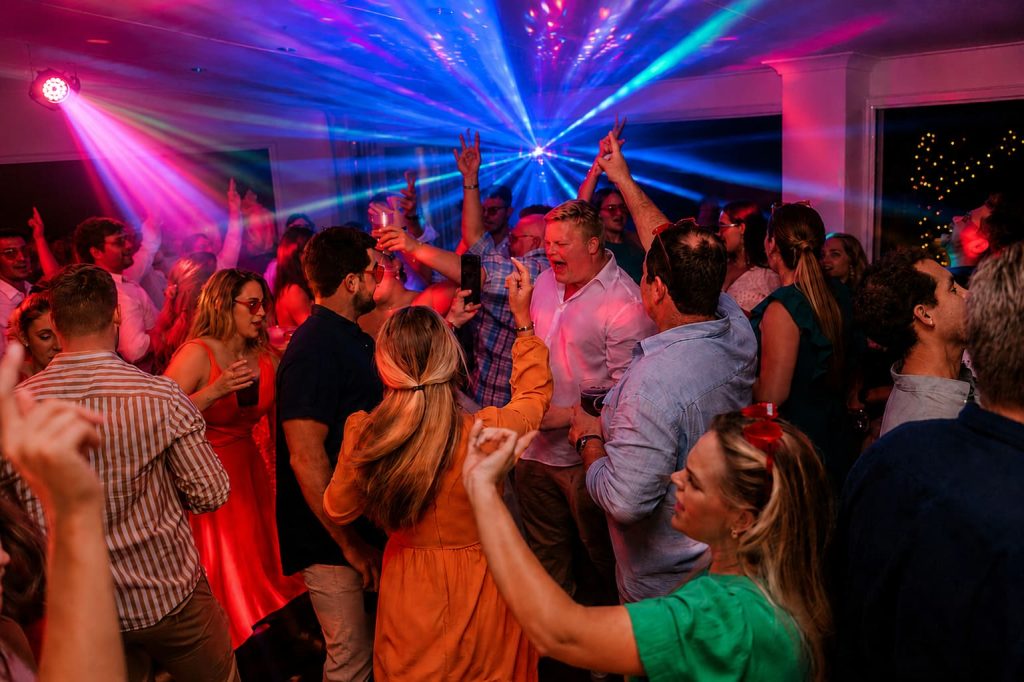 Packed wedding dancefloor with guests celebrating under vibrant DJ lighting and energetic party atmosphere on the KZN South Coast