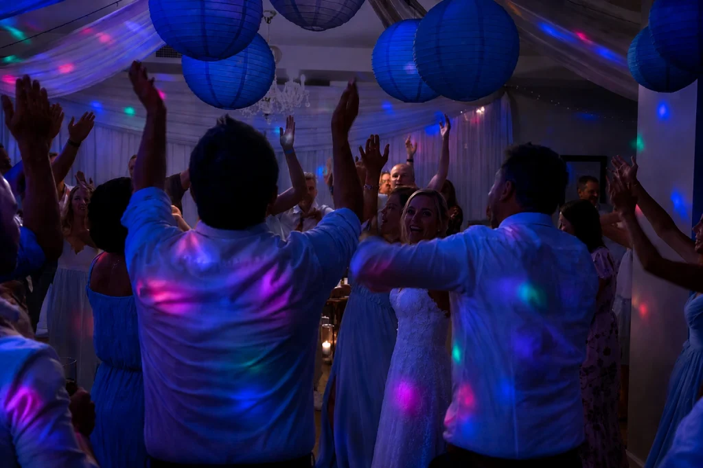 Wedding guests celebrating on the dance floor at Estuary Hotel under colourful DJ lighting and party atmosphere
